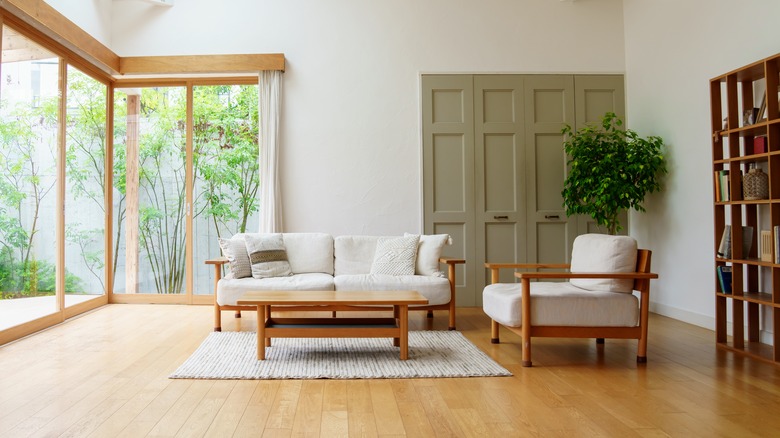 A spacious living room with wooden window frames, a bookcase, and seating area