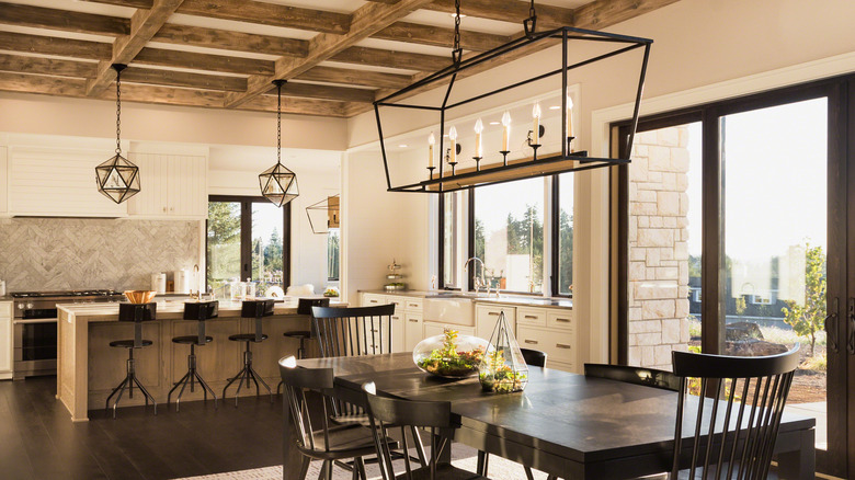 Open dining room and kitchen in featuring wood beam ceiling and other dark tones