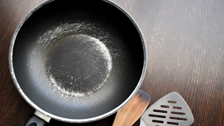 Scraped up non-stick pan with utensils on counter