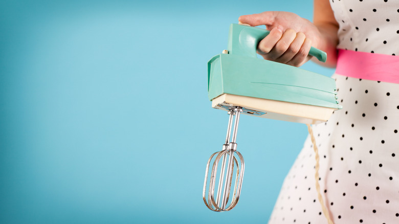 Person holding vintage hand mixer