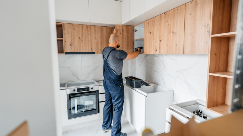 Man fitting in new cabinets in a kitchen