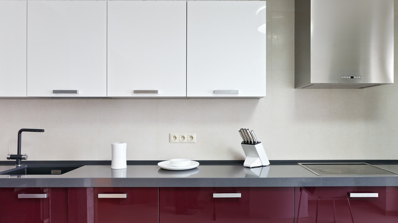 A modern kitchen with maroon and white cabinets