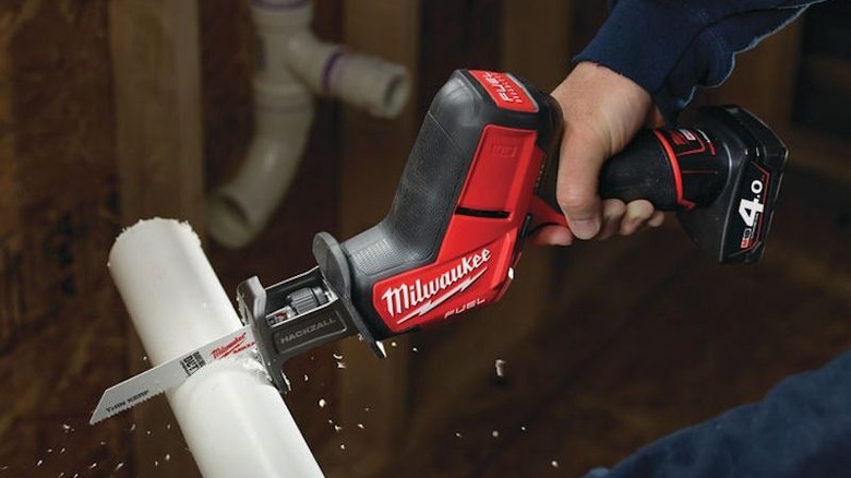 Close-up of a person cutting plastic pipe with Milwaukee's M12 HACKZALL Reciprocating Saw