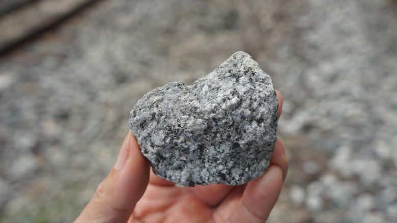 A fragment of raw granite rock on hand