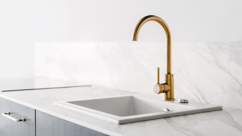 Spare white marble countertop and backsplash with gold faucet