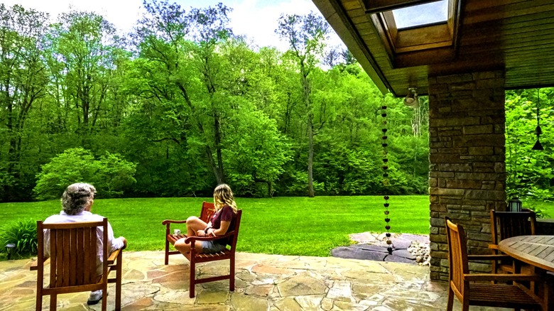 Two people in patio chairs on stone patio with rustic overhang