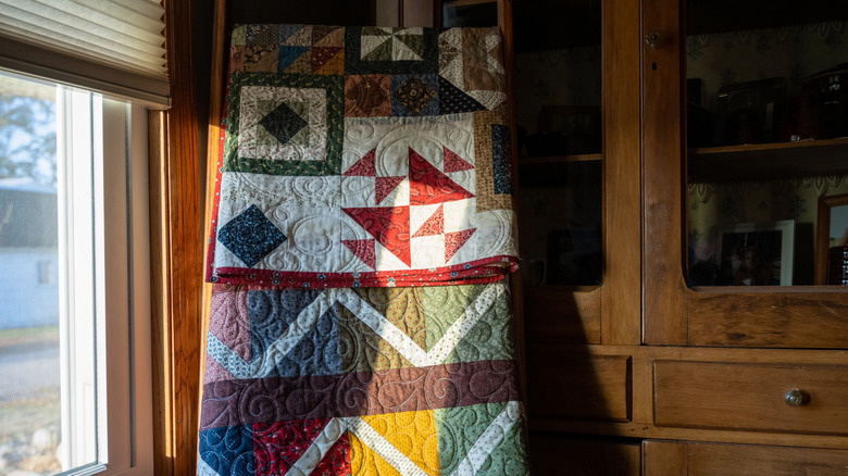 Colorful quilts on a rack by a window