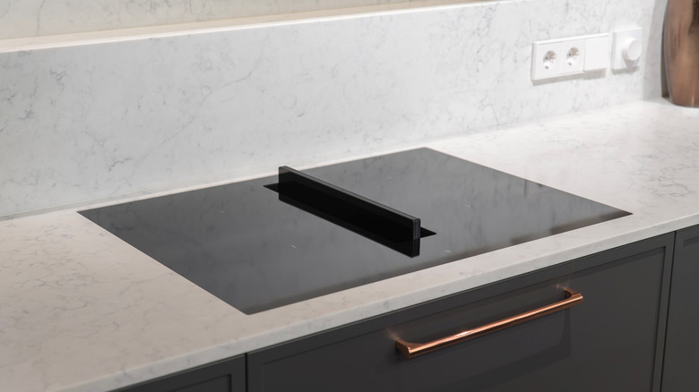 A black induction stove with a an in-built downdraft extractor