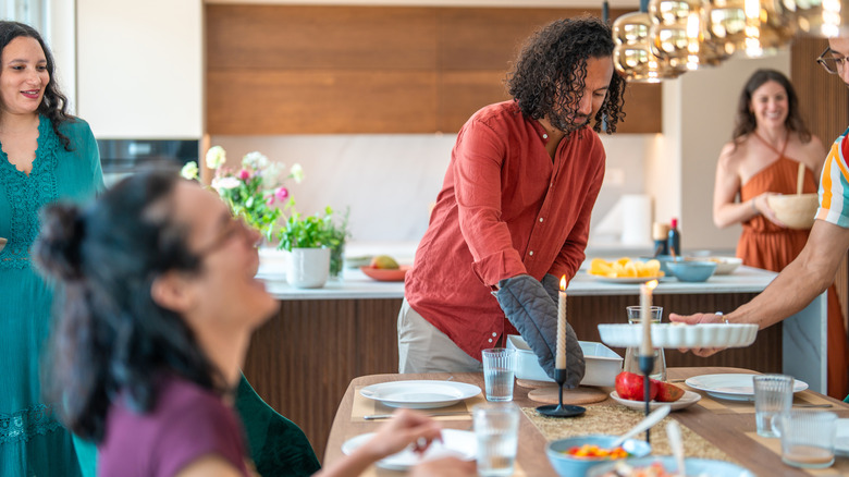 Person in a red shirt serving food at a party