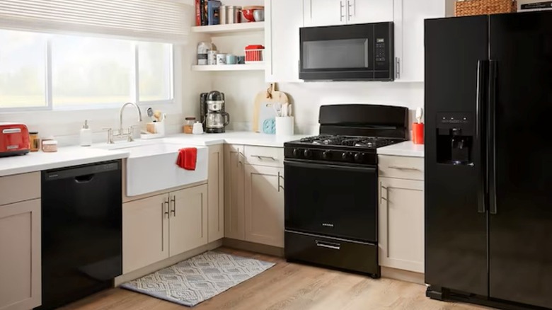 A black Amana oven installed in a kitchen next to a fridge