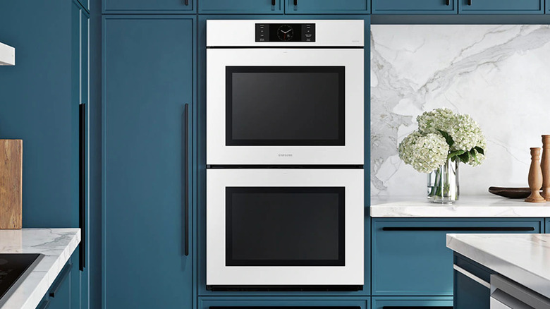 An oven and microwave combo with blue kitchen cabinets