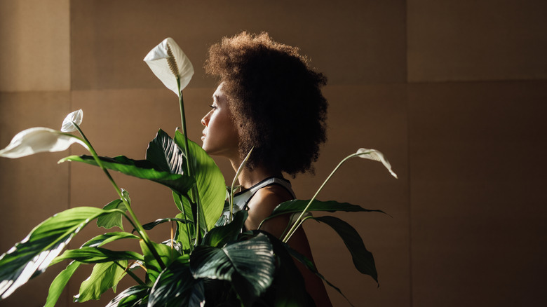 Woman standing behind a peace lily