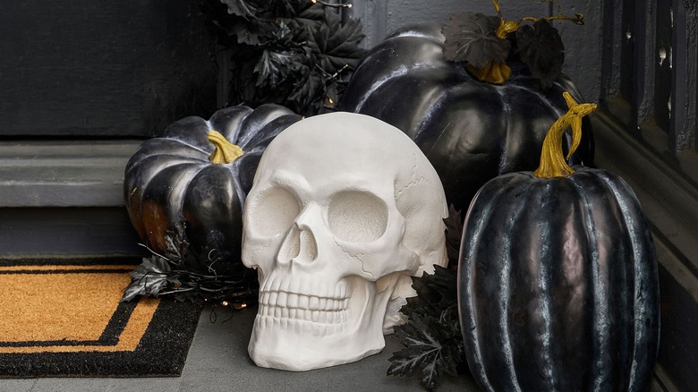 Skeleton head and faux black pumpkins on front porch