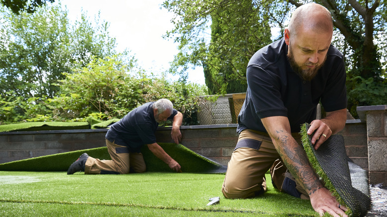 Two professionals installing artificial turf