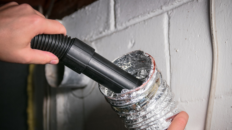 A person clearing dryer ducts of lint with a vacuum cleaner