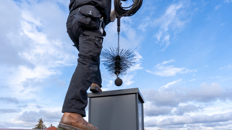A chimney sweep working to clear a chimney from above