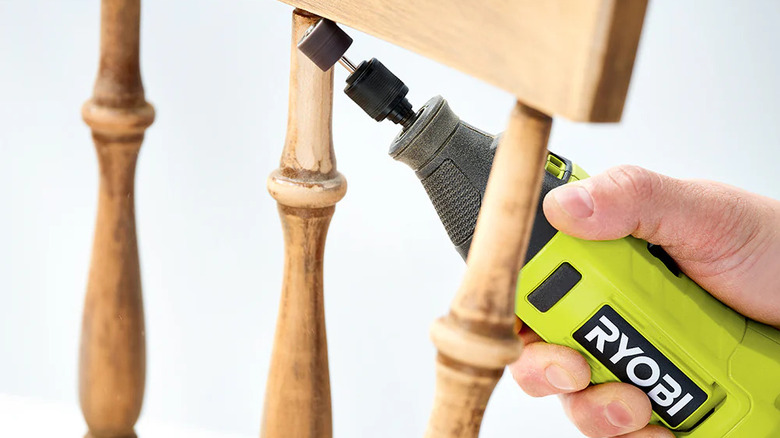 Close-up of someone using Ryobi's 1.2 Amp Rotary Tool to sand between the spindles of a wooden chair