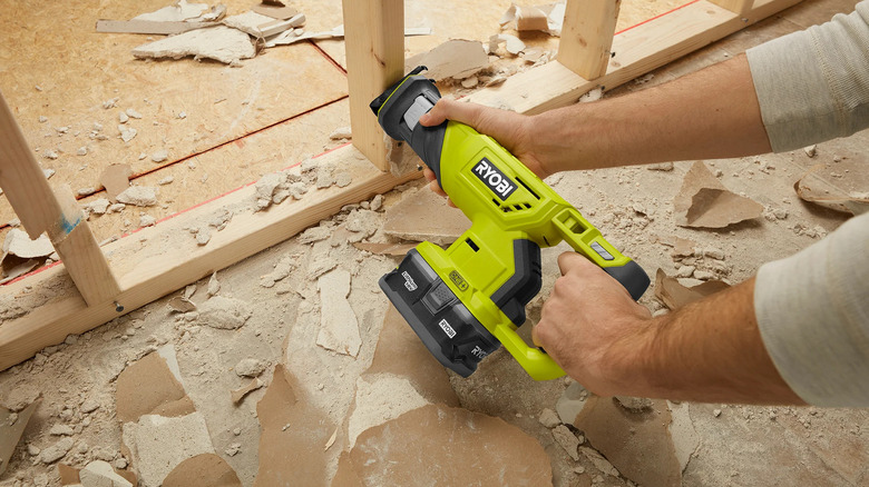 A person using Ryobi's 18V One+ Reciprocating Saw to cut through timber frames
