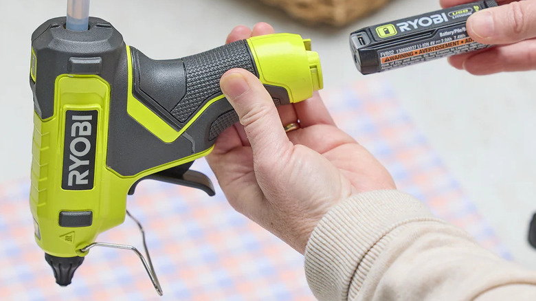 Close-up of a person loading Ryobi's USB Lithium Glue Gun with a battery