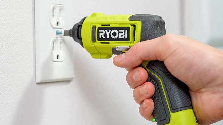 Close-up of a person using Ryobi's USB Lithium Multi-Head Screwdriver on a power socket