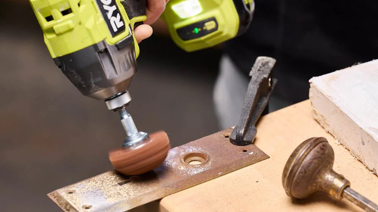 Close-up of a person using a Ryobi wire brush and drill to clean surface rust