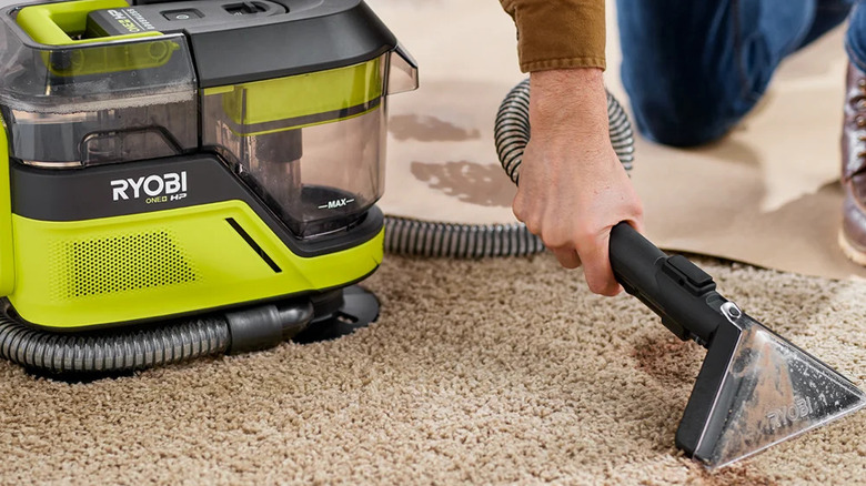 A person cleaning a soiled carpet with Ryobi's 18V cordless SwiftClean mid-size spot and carpet cleaner﻿