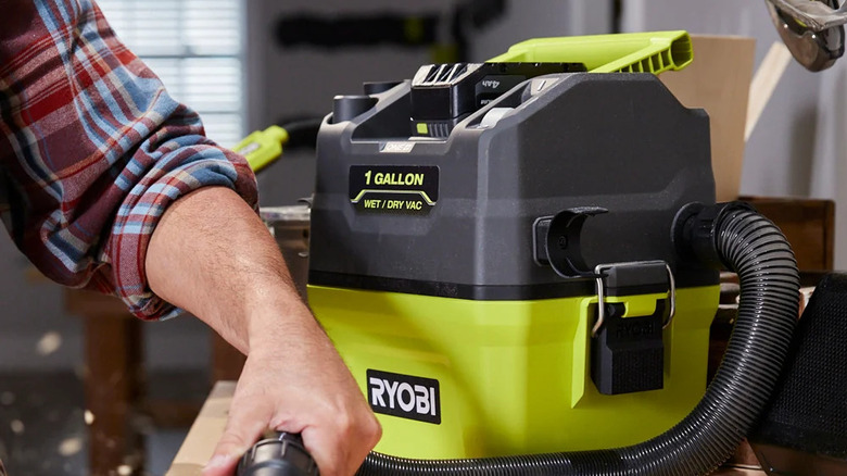 Close-up of a person using Ryobi's 18V One+ cordless 1-gallon wet/dry vacuum