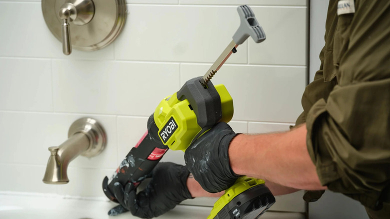 A person re-sealing a tub with Ryobi's 18V One+ cordless 10-ounce caulk and adhesive gun