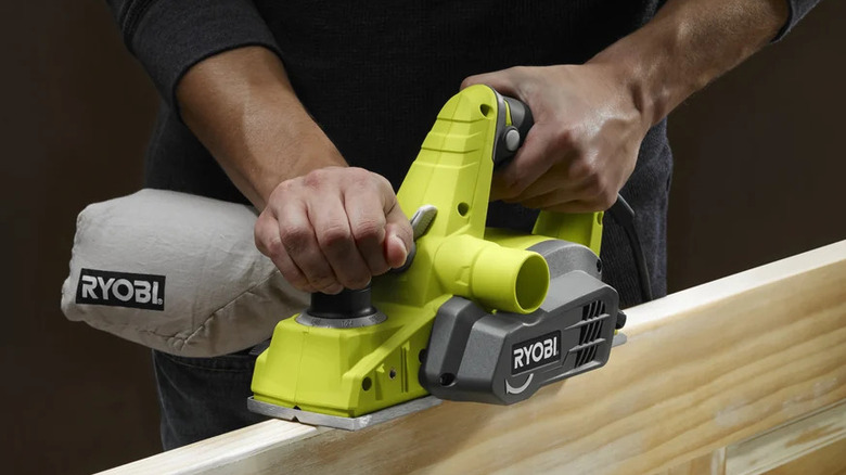 A person planing wood with Ryobi's 6-amp corded 3-¼-inch hand planer