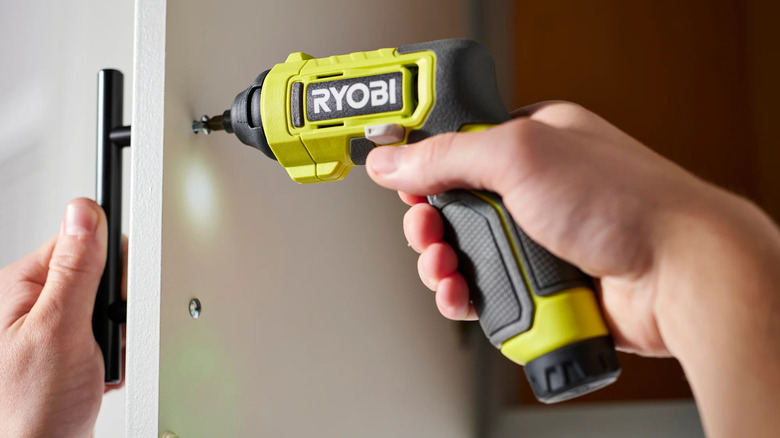 A person fixing hardware to a cabinet door with Ryobi's USB lithium multi-head screwdriver