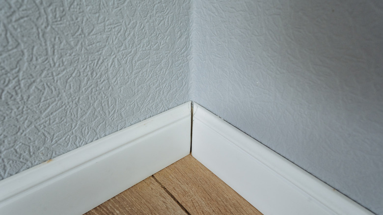A gap between two floorboards that are meeting in a corner.