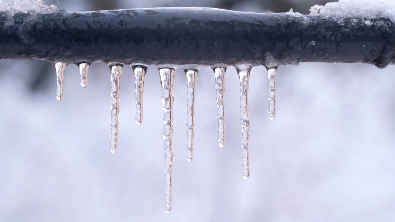 A frozen grey pipe with icicles