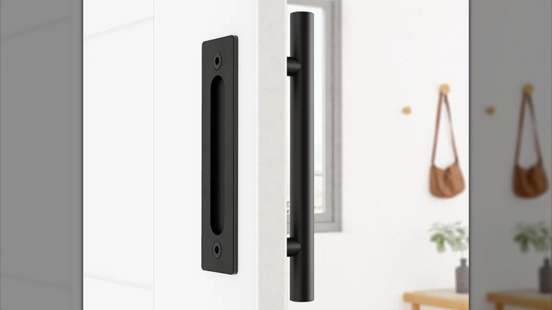 A two-sided black closet handle is installed on a white closet door