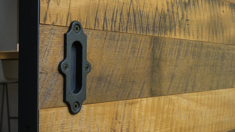 A Leatherneck Hardware cast iron closet door pull is installed on a unique sliding wood door