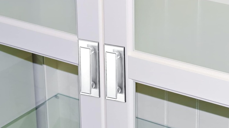 Two mirrored beveled door handles are installed on a set of white doors