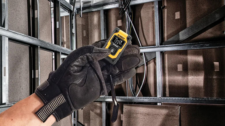 A gloved hand measuring with DeWalt's 55-foot Pocket Laser Distance Measurer