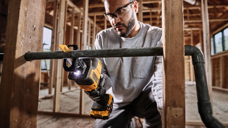 A person cutting metal pipework with DeWalt's Atomic 20V MAX Cordless Brushless Compact Reciprocating Saw