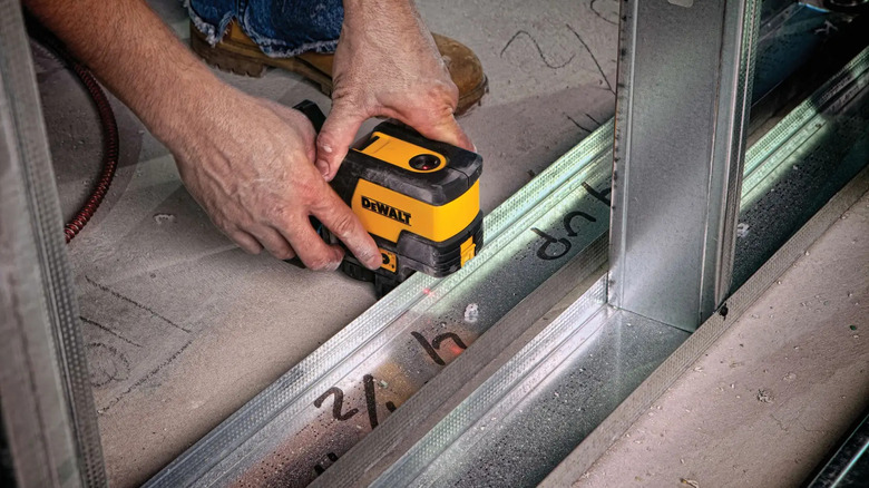 A person using DeWalt's 165 foot Red Self-Leveling Cross-Line and Plump Spot Laser Level