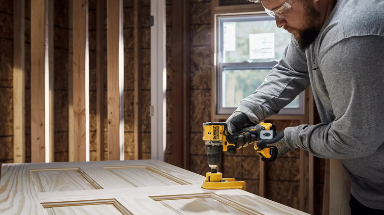A carpenter drilling into a door with DeWalt's Atomic 20V Lithium-Ion Cordless Compact ½-inch Drill/Driver Kit