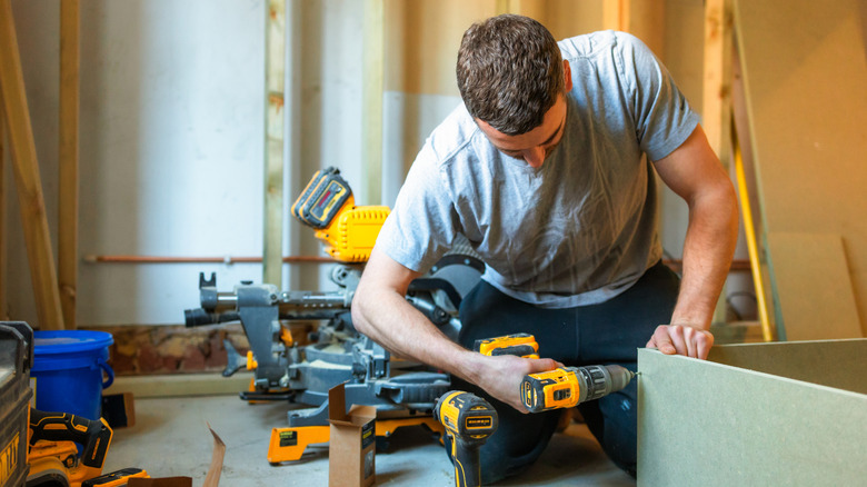 A young carpenter working with black and yellow power tools