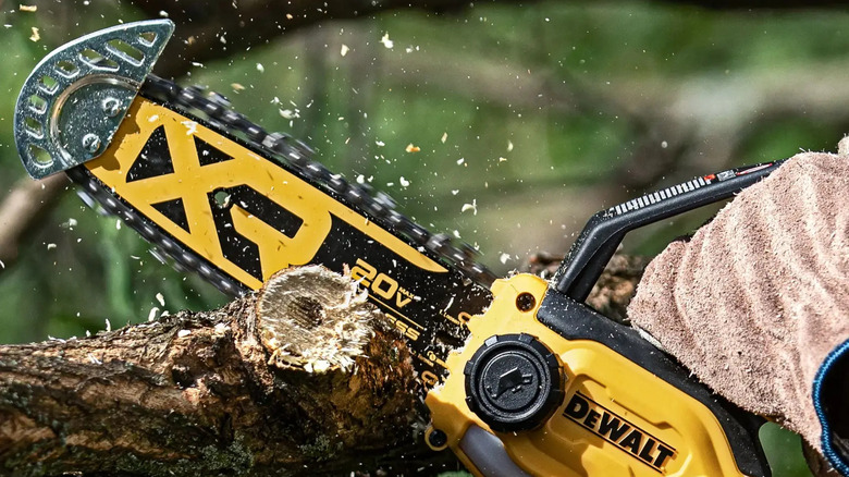 Close-up of a person chopping wood with DeWalt's 20V MAX 8-inch Brushless Cordless Pruning Mini Chainsaw
