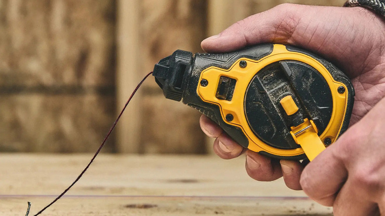 A person using DeWalt's 100 foot Chalk Reel Kit with Red Chalk