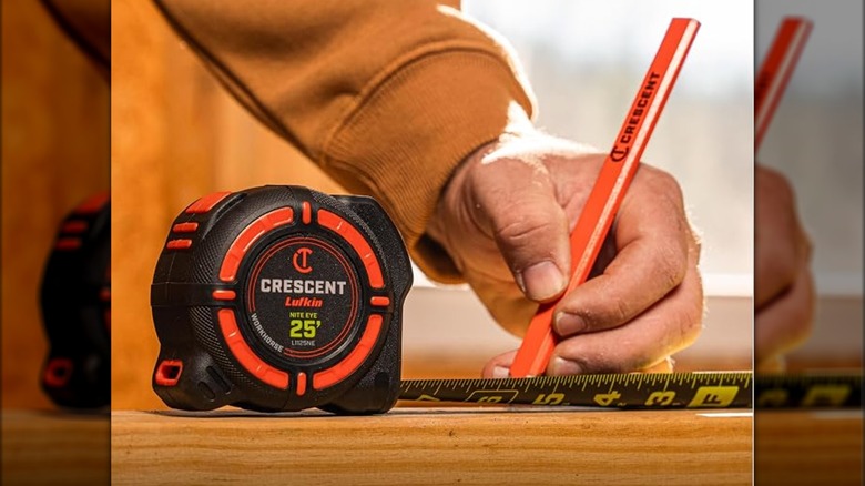 A person marking measurements using a pencil and Crescent's 1 ¼-inch x 25-foot Workhorse Nite Eye Tape Measure