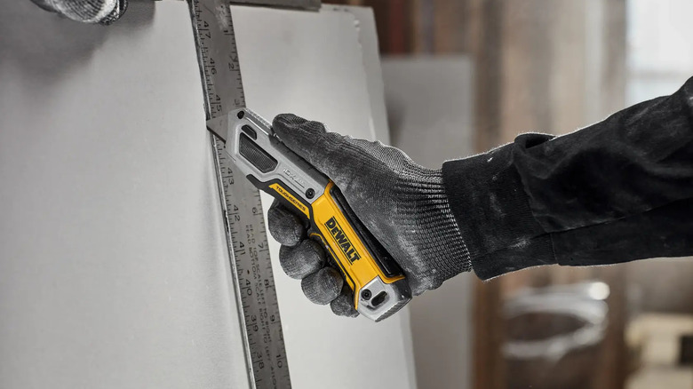 A person cutting drywall with DeWalt's Toughseries Retractable Utility Knife