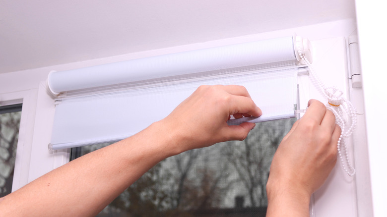 Close-up of a person fitting a blind to a window