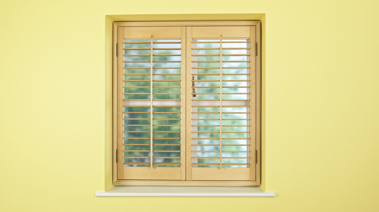 A small square window fitted with wooden shutters