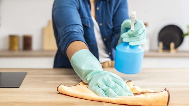 Woman wearing gloves cleaning kitchen countertop