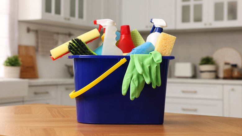 Bucket with cleaning supplies on table in kitchen