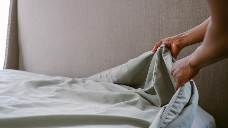Person taking sheets off the bed