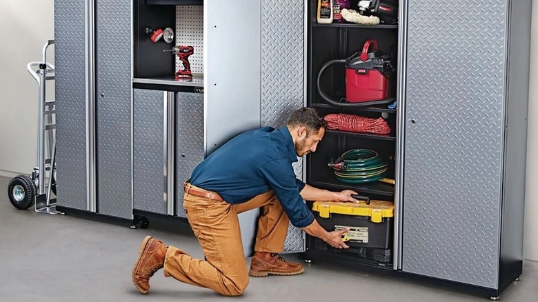 A man pulling a toolbox out of a large metal storage cabinet